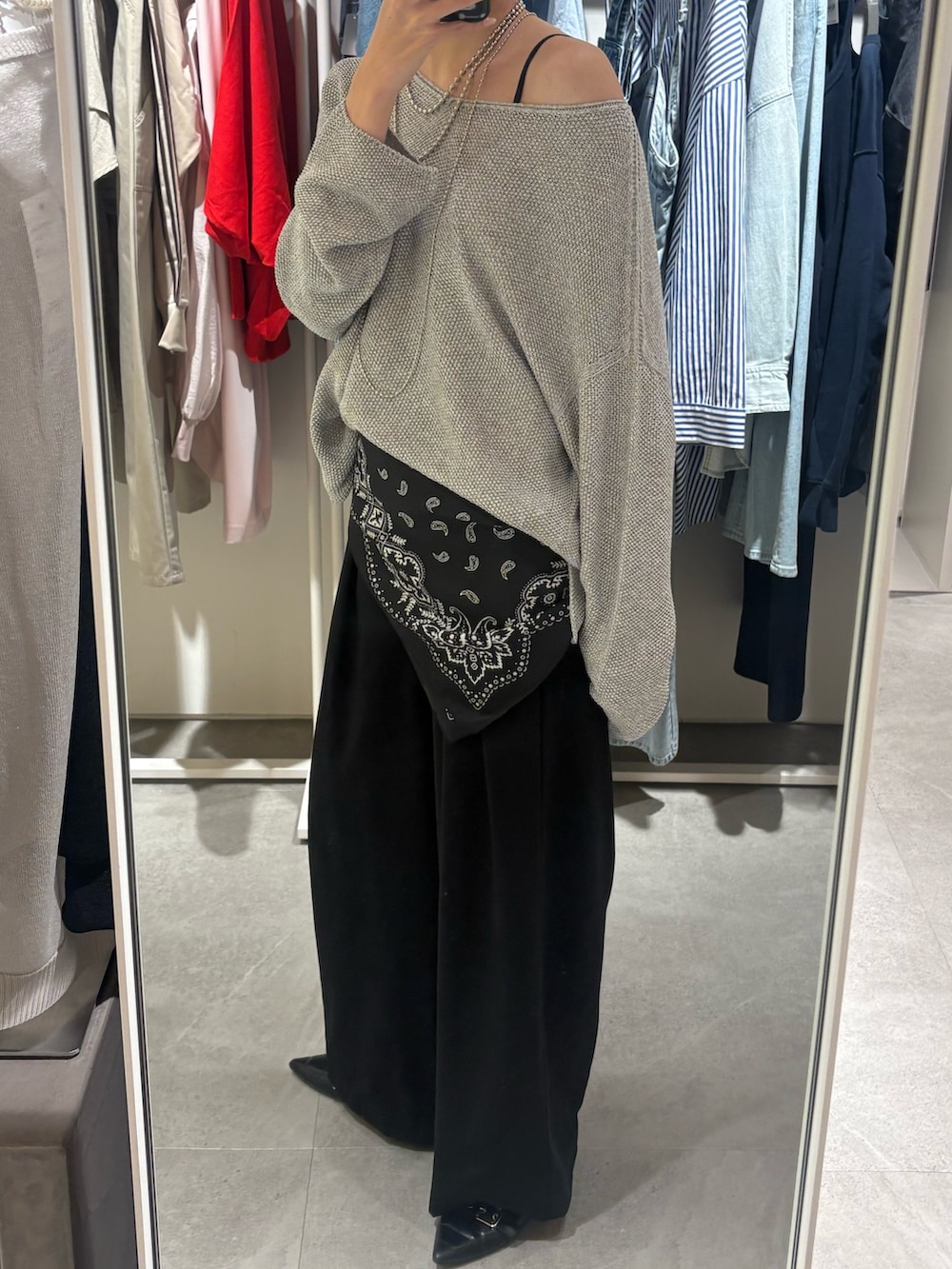 グレー系のニット/セーター、ブラック系のスラックス、シルバー系のネックレスを着用したレディースの春コーディネートの2枚目の写真