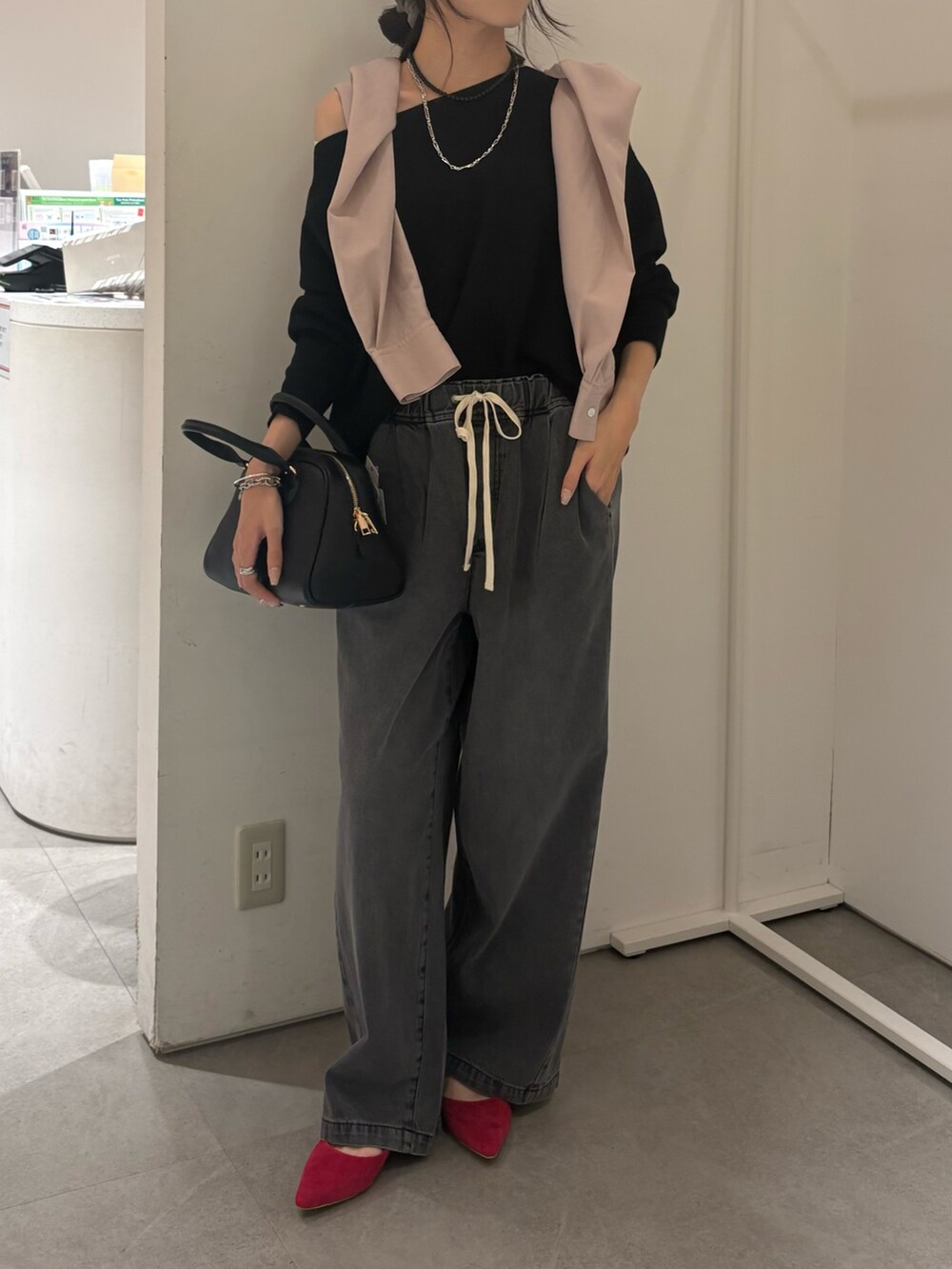 ピンク系のシャツ/ブラウス、ブラック系のニット/セーター、ブラック系のデニムパンツを着用したレディースの秋コーディネートの2枚目の写真