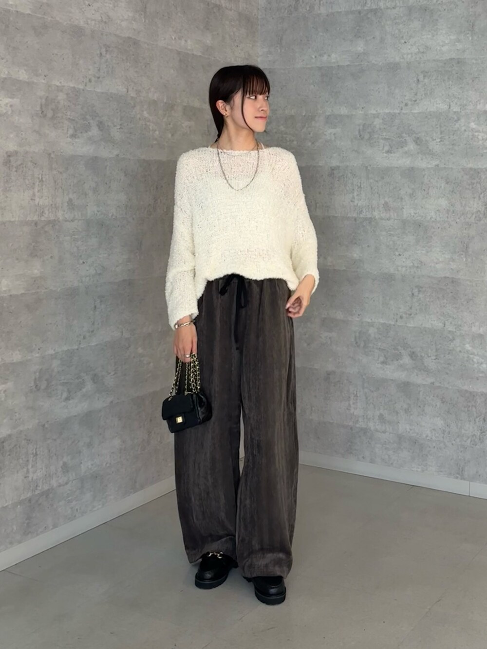 ホワイト系のニット/セーター、グレー系のその他パンツ、ブラック系のショルダーバッグを着用したレディースの秋コーディネートの2枚目の写真