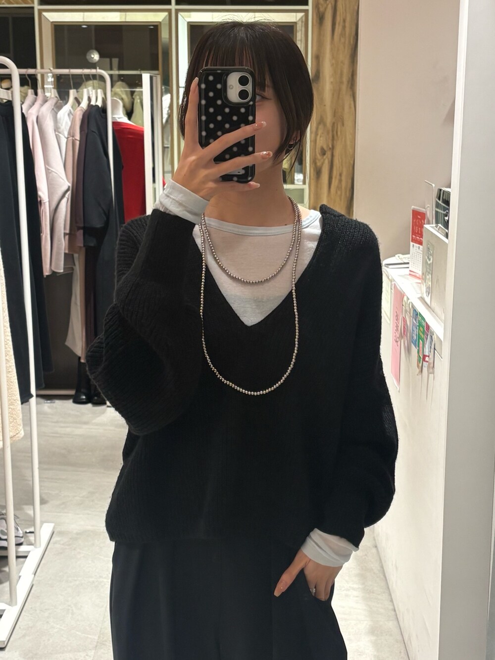 ブラック系のニット/セーター、ブルー系のTシャツ/カットソー、ブラック系のスラックスを着用したレディースの冬コーディネートの3枚目の写真