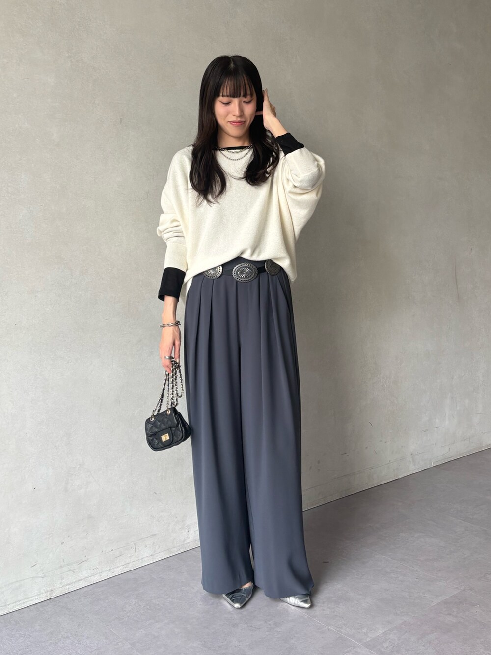 ホワイト系のニット/セーター、グレー系のスラックス、ブラック系のTシャツ/カットソーを着用したレディースの冬コーディネートの2枚目の写真