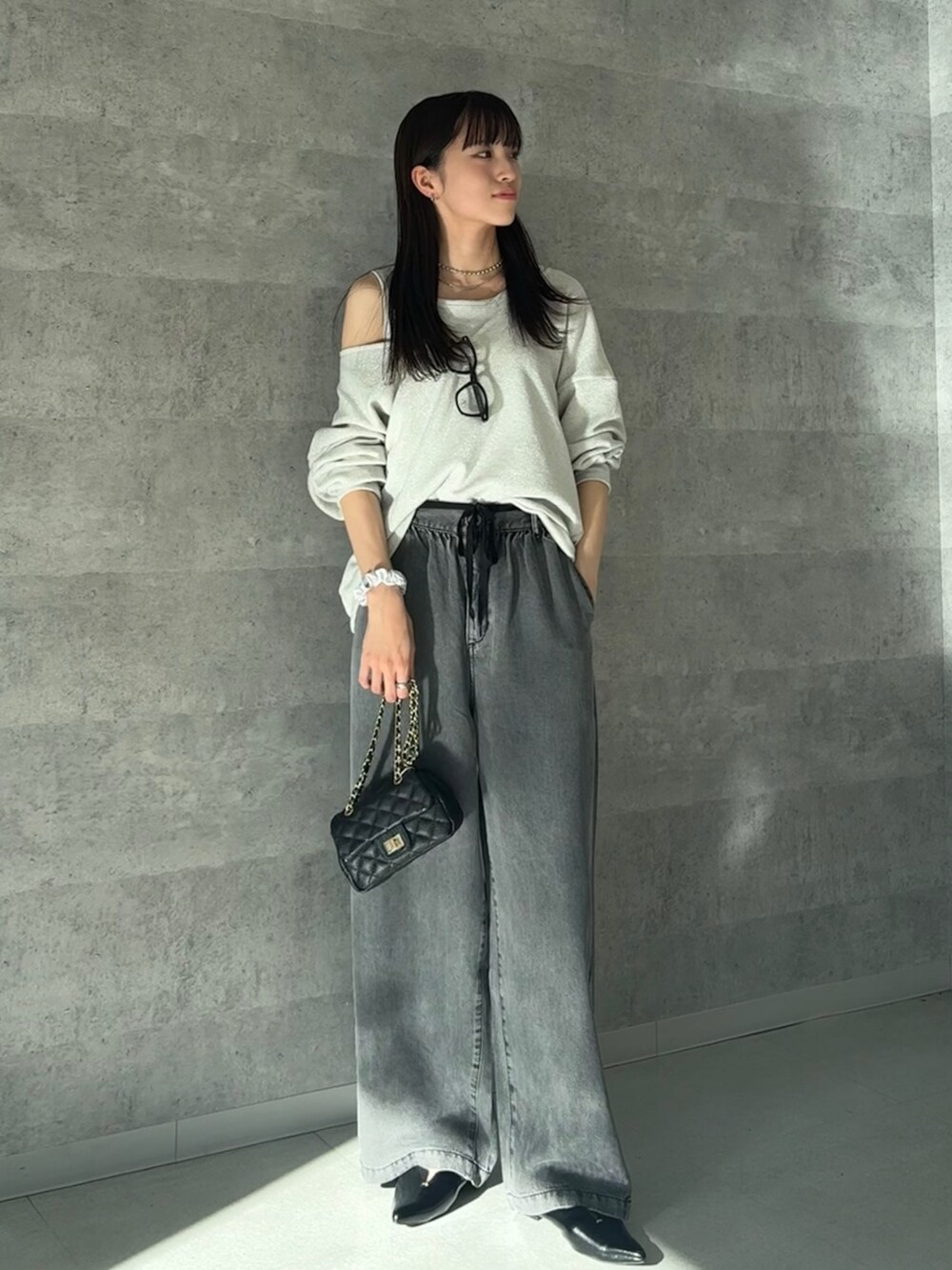 グレー系のTシャツ/カットソー、ブラック系のデニムパンツ、ブラック系のショルダーバッグを着用したレディースの秋コーディネートの3枚目の写真