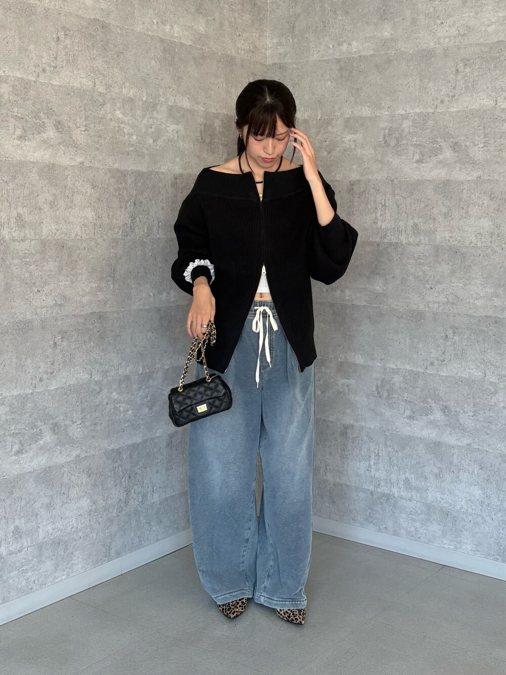 ブラック系のニット/セーター、ブラック系のショルダーバッグ、ブルー系のその他パンツを着用したレディースの秋コーディネートの3枚目の写真