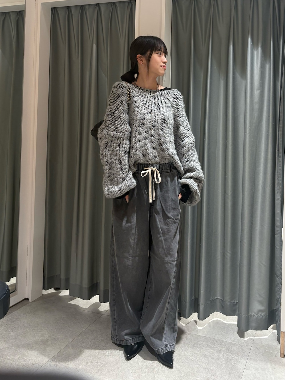 グレー系のニット/セーター、ブラック系のTシャツ/カットソー、ブラック系のデニムパンツを着用したレディースの秋コーディネートの2枚目の写真