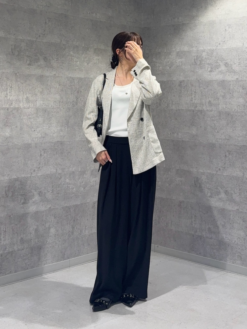 ホワイト系のテーラードジャケット、ホワイト系のニット/セーター、ブラック系のスラックスを着用したレディースの春コーディネートの3枚目の写真