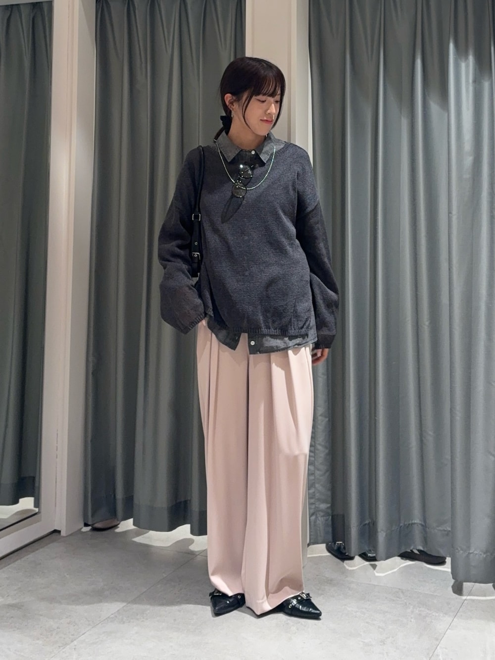 ブラック系のシャツ/ブラウス、グレー系のニット/セーター、ピンク系のスラックスを着用したレディースの春コーディネートの2枚目の写真