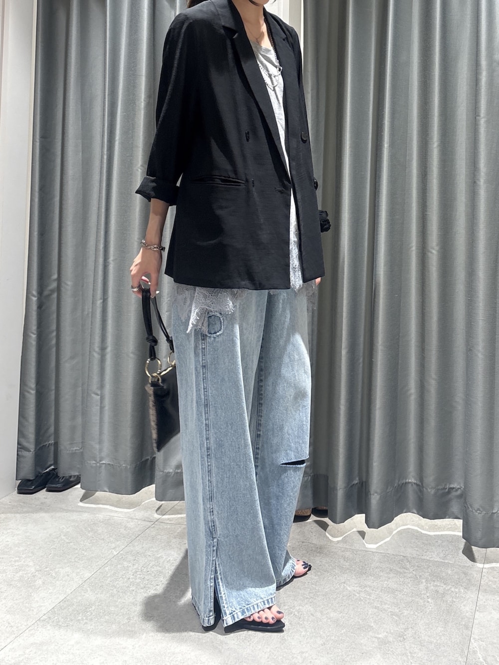 ブラック系のテーラードジャケット、グレー系のTシャツ/カットソー、ブルー系のデニムパンツを着用したレディースの春コーディネートの3枚目の写真