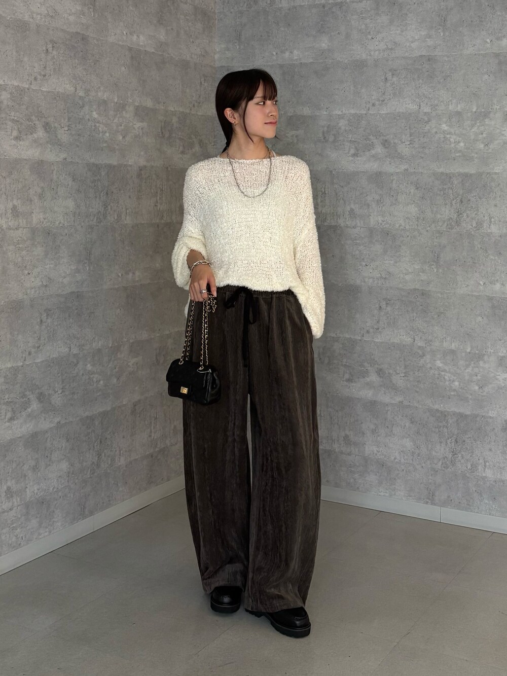 ホワイト系のニット/セーター、グレー系のその他パンツ、ブラック系のショルダーバッグを着用したレディースの秋コーディネートの3枚目の写真