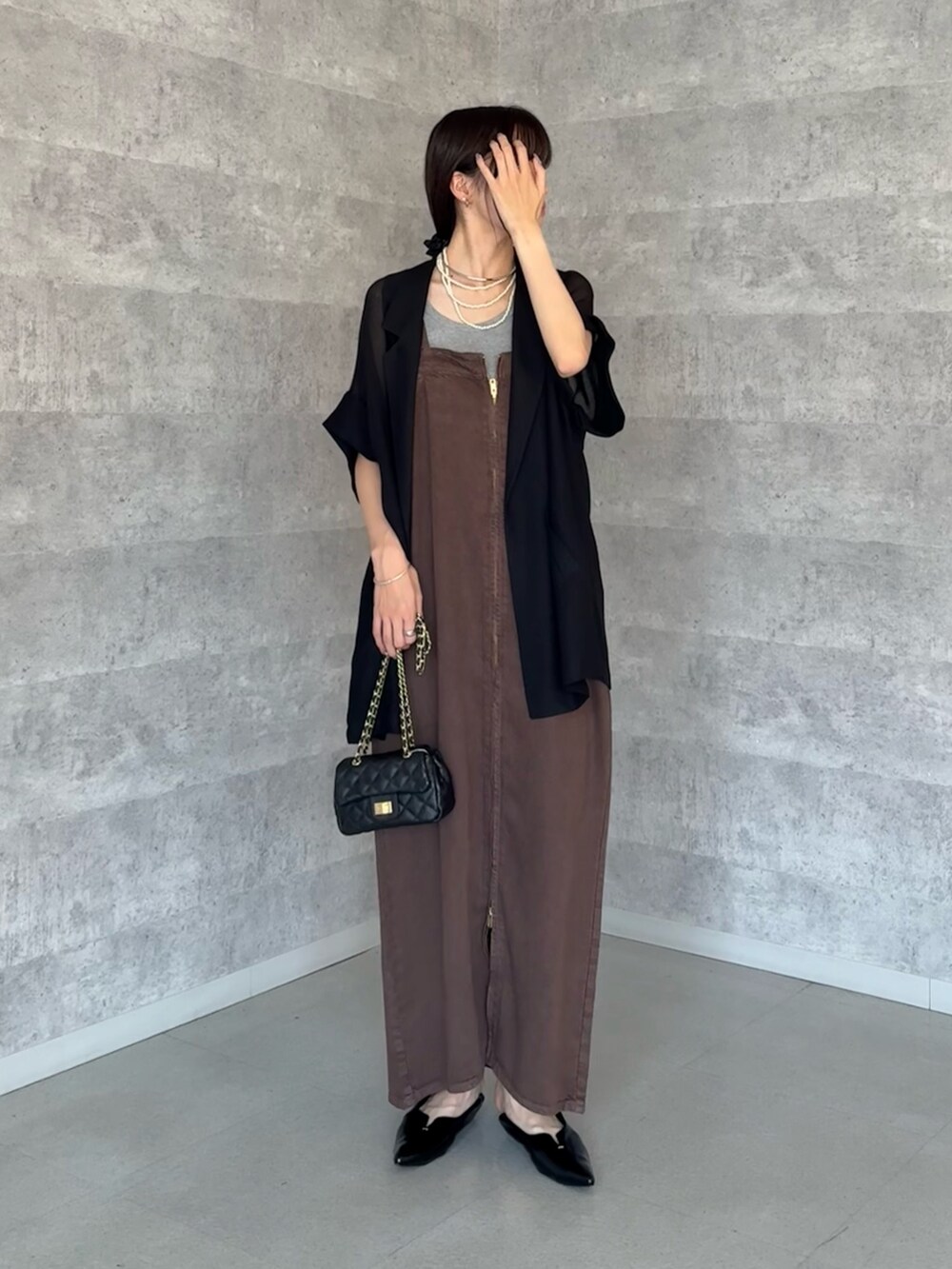 ブラック系のテーラードジャケット、ブラウン系のワンピース、ブラック系のショルダーバッグを着用したレディースの夏コーディネートの3枚目の写真