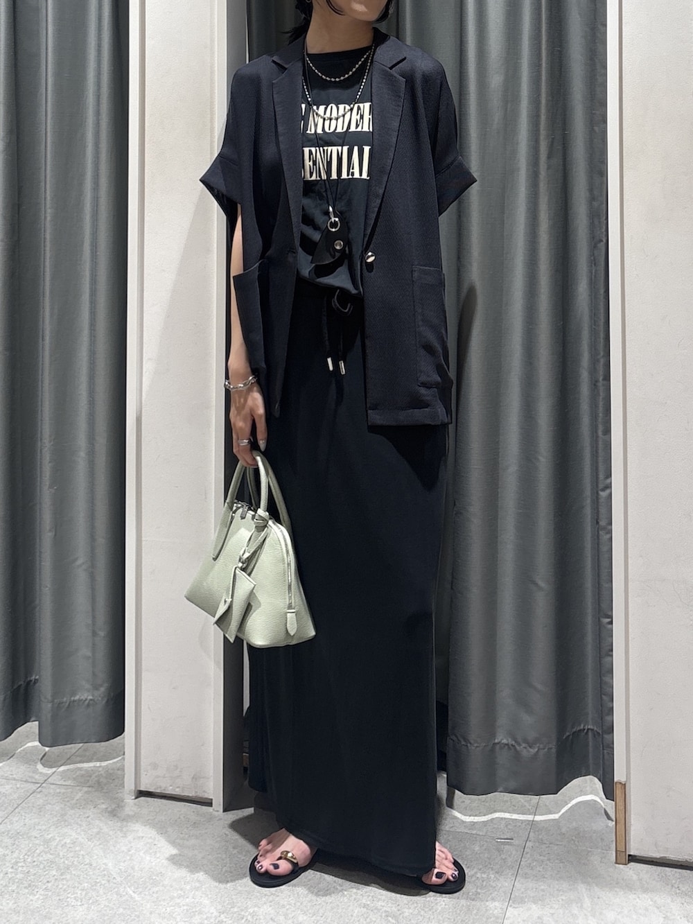 グレー系のテーラードジャケット、ブラック系のTシャツ/カットソー、ブラック系のスカートを着用したレディースの夏コーディネートの2枚目の写真