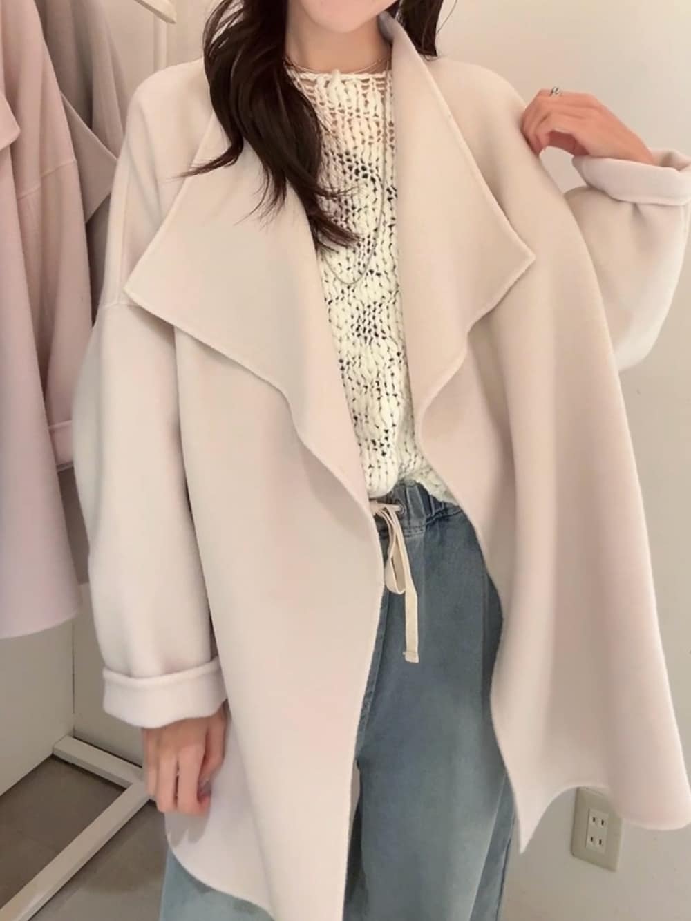 ブラック系のその他アウター、ホワイト系のニット/セーター、ブルー系のデニムパンツを着用したレディースの冬コーディネートの4枚目の写真