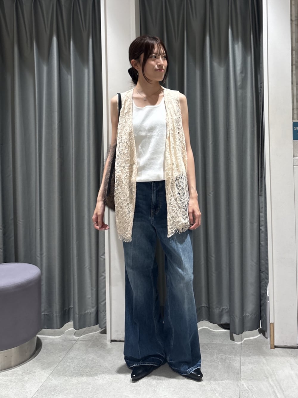 ホワイト系のベスト、ホワイト系のタンクトップ、ブルー系のデニムパンツを着用したレディースの秋コーディネートの2枚目の写真