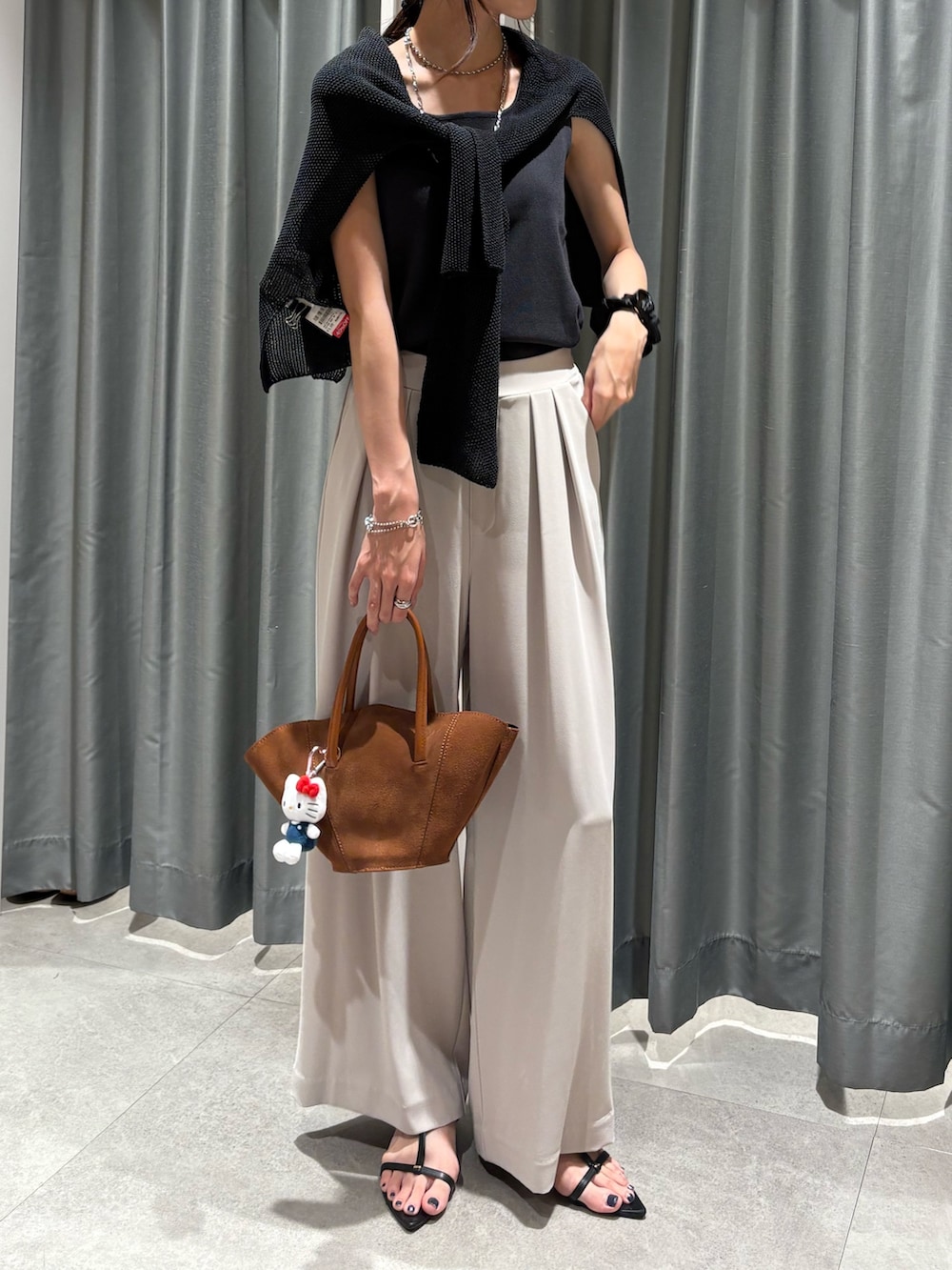 グレー系のスラックス、グレー系のタンクトップ、ブラック系のニット/セーターを着用したレディースの夏コーディネートの2枚目の写真