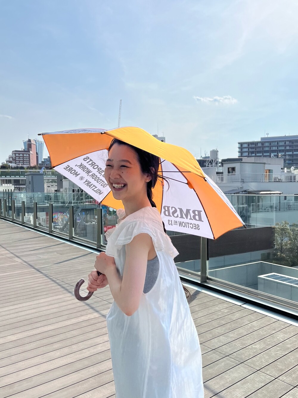 ホワイト系のワンピース、オレンジ系の長傘を着用したレディースの夏コーディネートの8枚目の写真