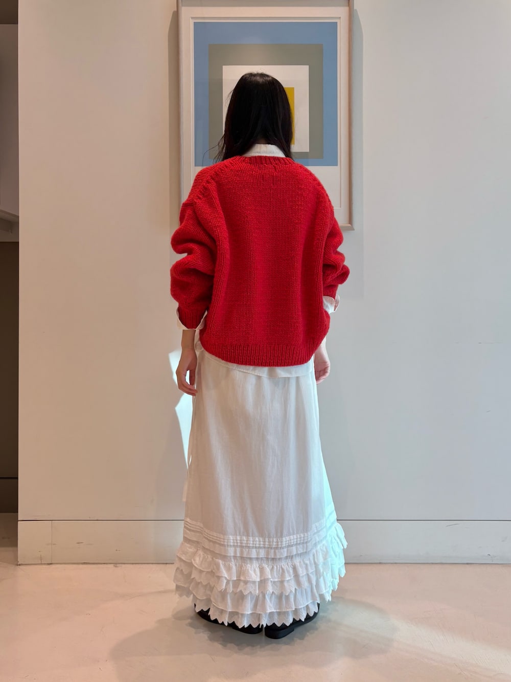 レッド系のニット/セーター、ホワイト系のスカートを着用したレディースの秋コーディネートの3枚目の写真