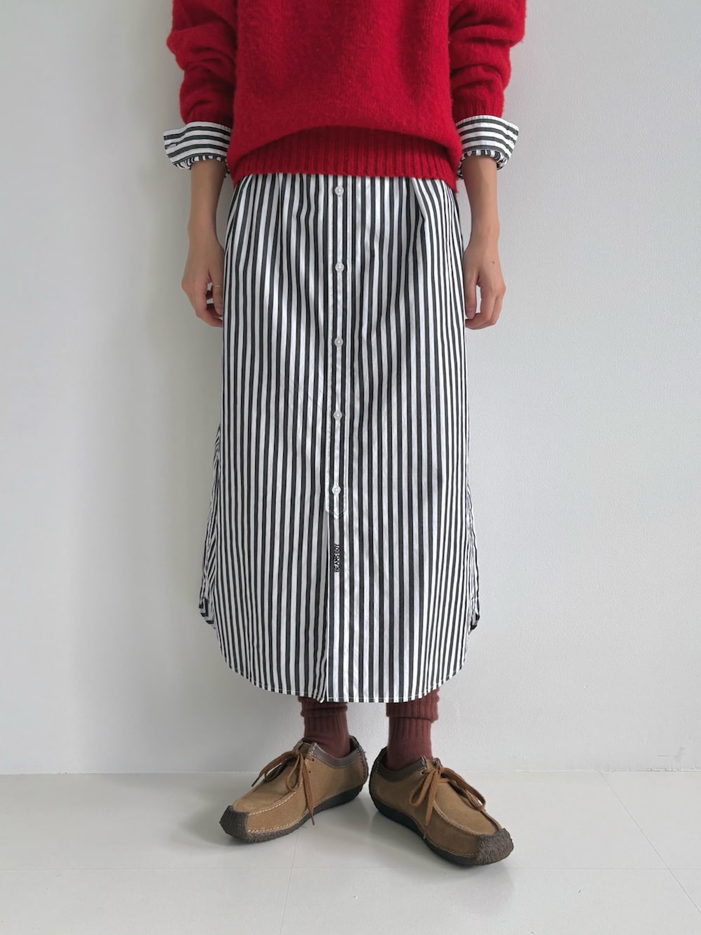 レッド系のニット/セーター、ブラック系のシャツワンピース、ブラウン系のモカシン/デッキシューズを着用したレディースの秋コーディネートの7枚目の写真