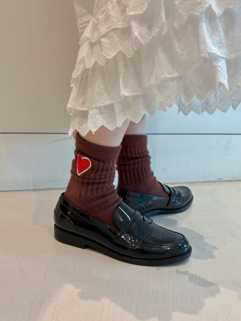 レッド系のニット/セーター、ホワイト系のスカートを着用したレディースの秋コーディネートの7枚目の写真