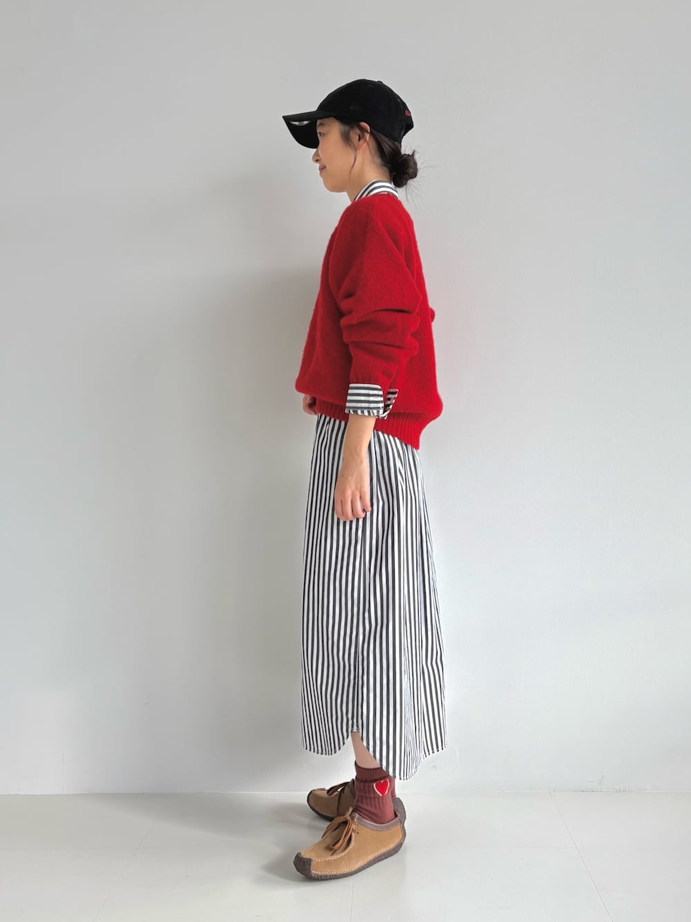 レッド系のニット/セーター、ブラック系のシャツワンピース、ブラウン系のモカシン/デッキシューズを着用したレディースの秋コーディネートの2枚目の写真