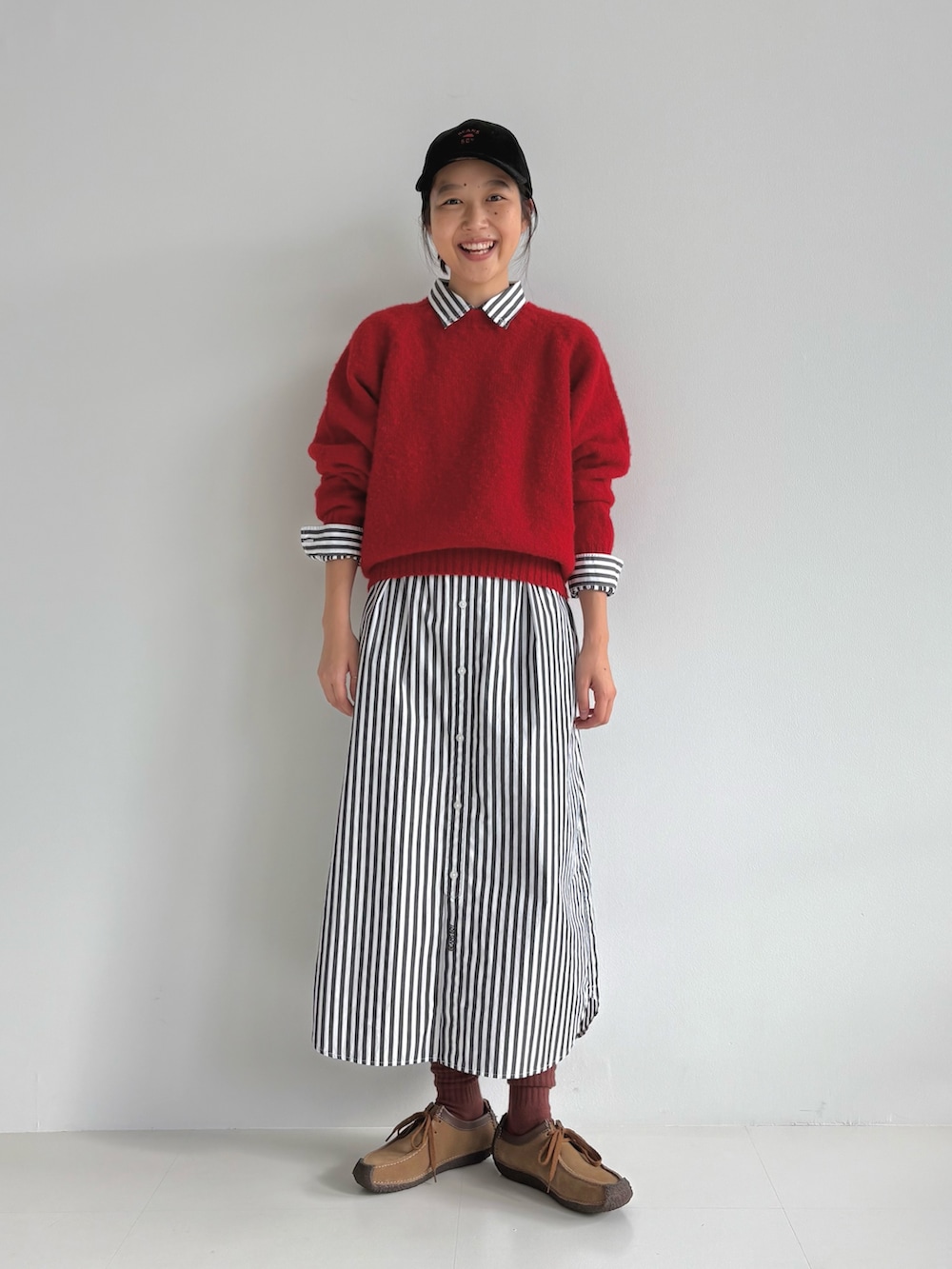 レッド系のニット/セーター、ブラック系のシャツワンピース、ブラウン系のモカシン/デッキシューズを着用したレディースの秋コーディネートの4枚目の写真