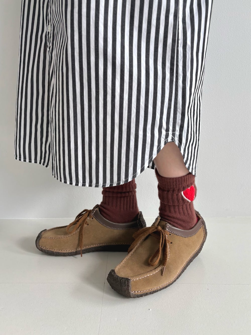 レッド系のニット/セーター、ブラック系のシャツワンピース、ブラウン系のモカシン/デッキシューズを着用したレディースの秋コーディネートの8枚目の写真