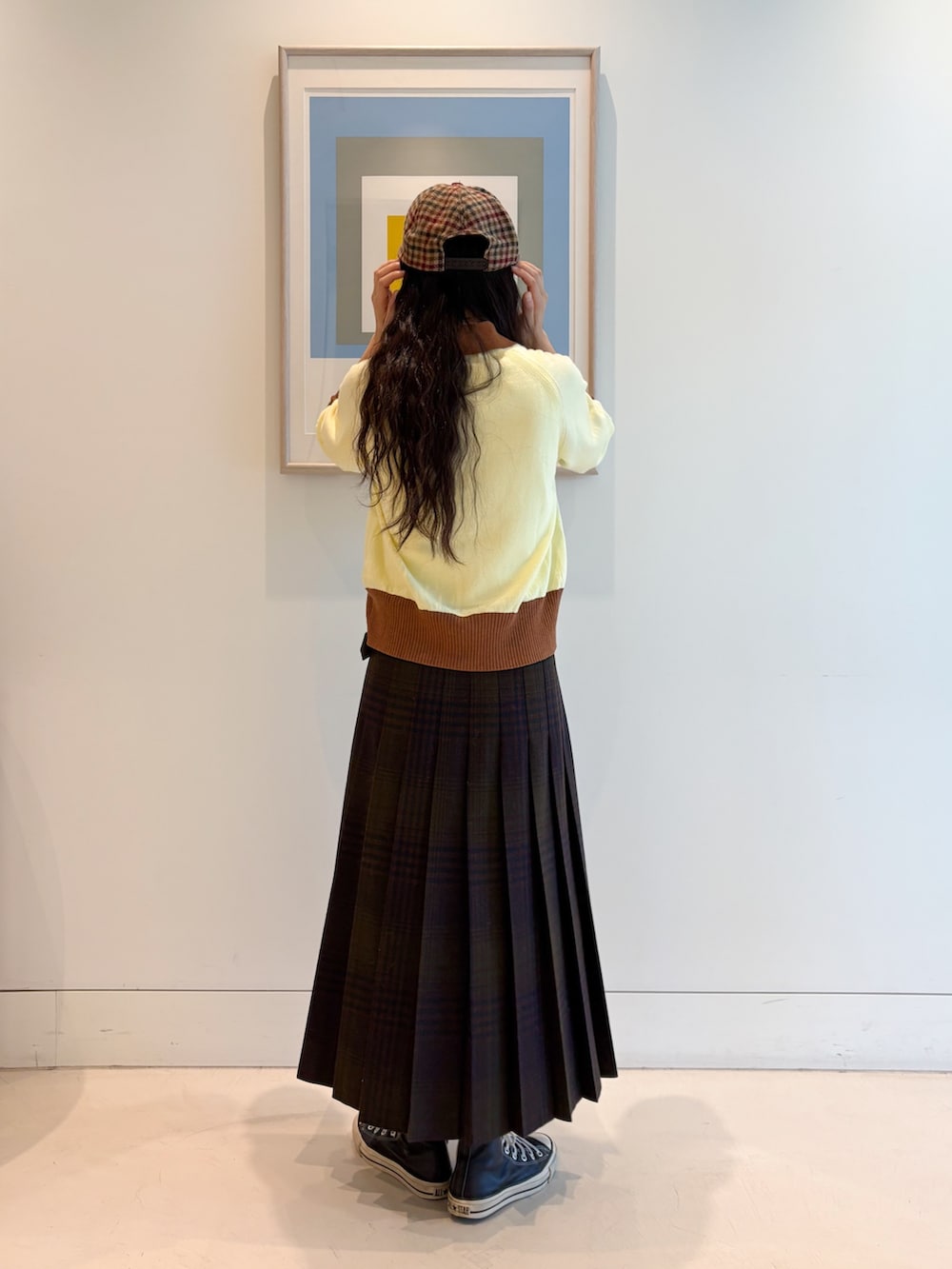 イエロー系のニット/セーター、ブルー系のスカートを着用したレディースの秋コーディネートの3枚目の写真