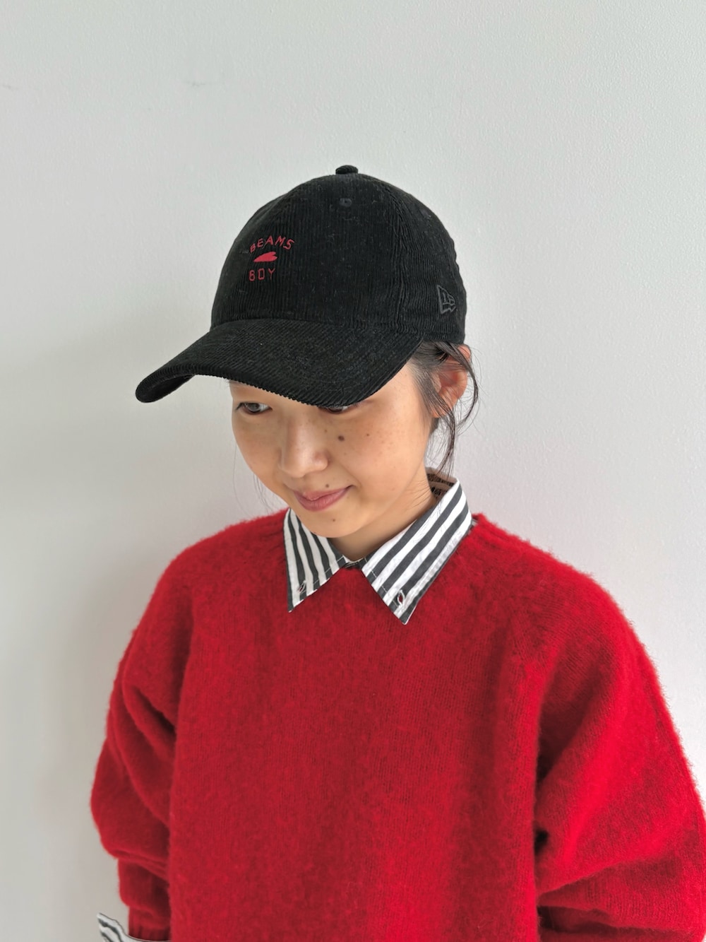 レッド系のニット/セーター、ブラック系のシャツワンピース、ブラウン系のモカシン/デッキシューズを着用したレディースの秋コーディネートの6枚目の写真