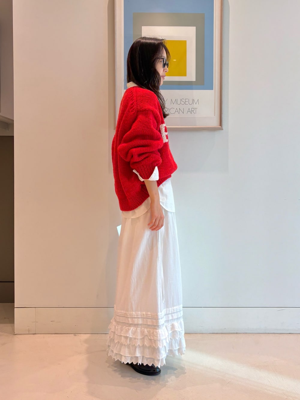 レッド系のニット/セーター、ホワイト系のスカートを着用したレディースの秋コーディネートの2枚目の写真
