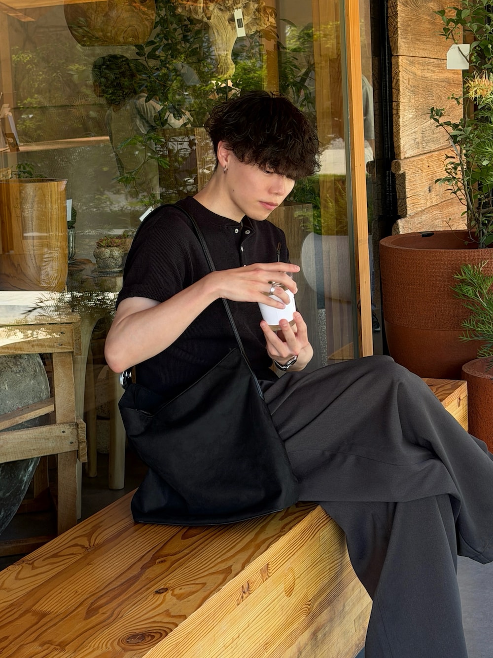ブラック系のTシャツ/カットソー、グレー系のスラックス、ブラック系のショルダーバッグを着用したメンズの夏コーディネートの3枚目の写真