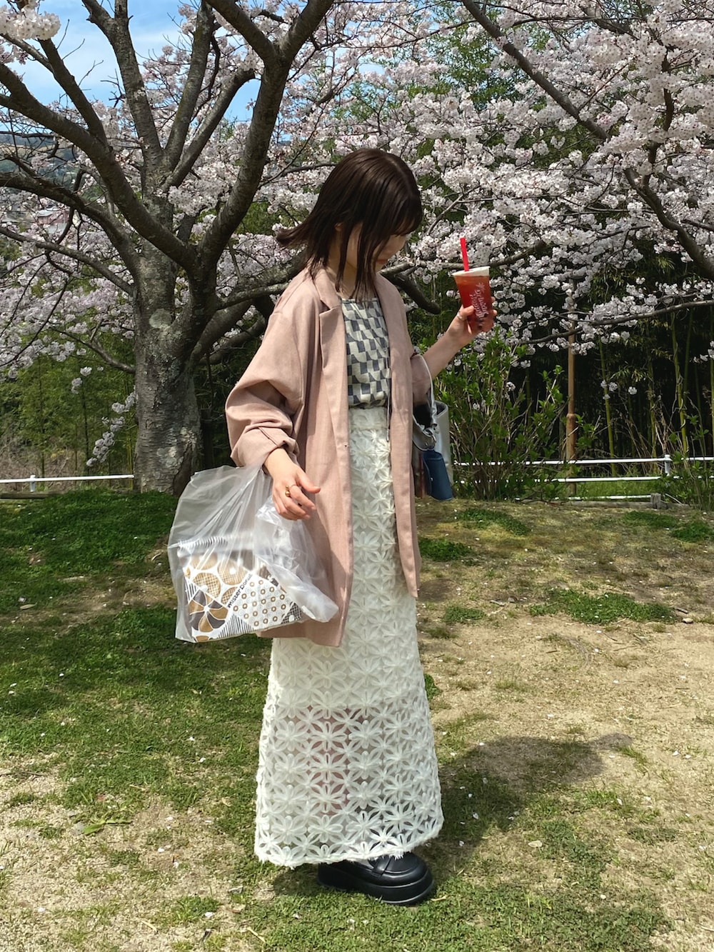 ピンク系のテーラードジャケット、ホワイト系のスカート、シルバー系のショルダーバッグを着用したレディースの春コーディネートの2枚目の写真