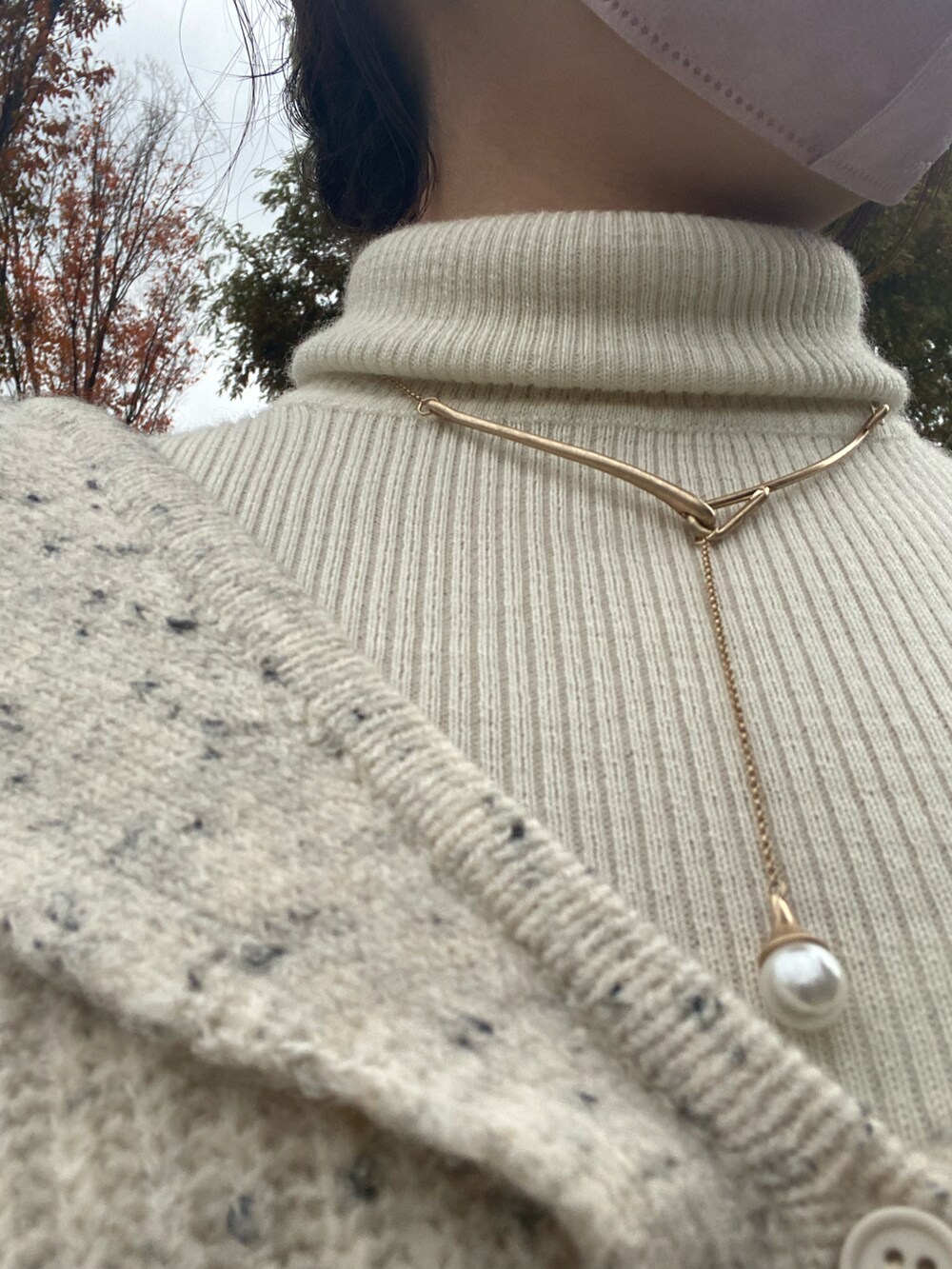 ホワイト系のカーディガン/ボレロ、ブラック系のスカート、ブラック系のブーツを着用したレディースの秋コーディネートの2枚目の写真