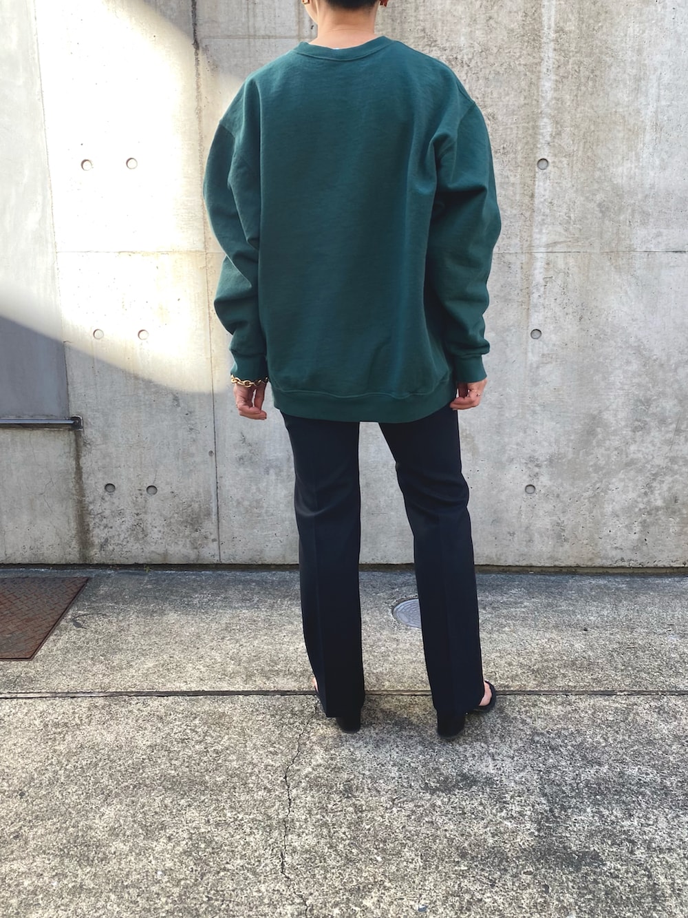 グリーン系のスウェット、ブラック系のスラックスを着用したレディースの冬コーディネートの3枚目の写真