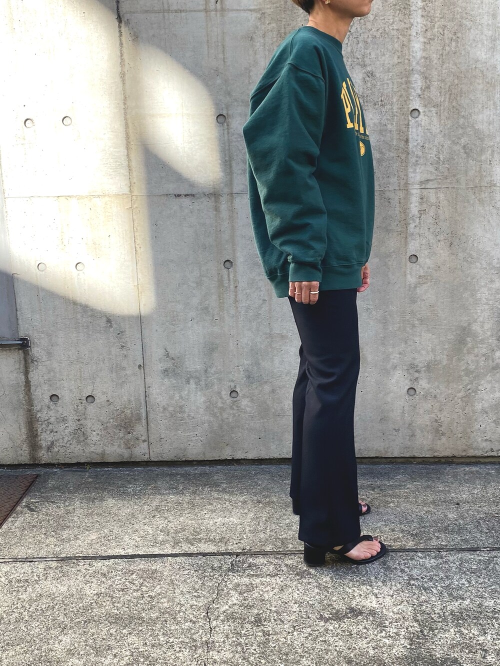 グリーン系のスウェット、ブラック系のスラックスを着用したレディースの冬コーディネートの2枚目の写真