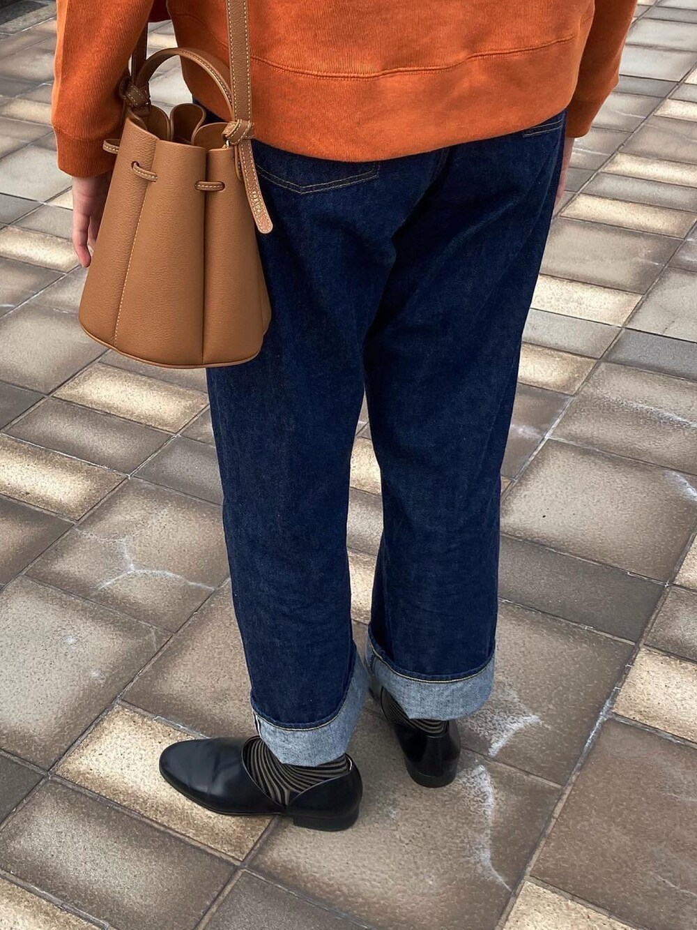 オレンジ系のカーディガン/ボレロ、ホワイト系のTシャツ/カットソー、ブルー系のデニムパンツを着用したレディースの秋コーディネートの3枚目の写真