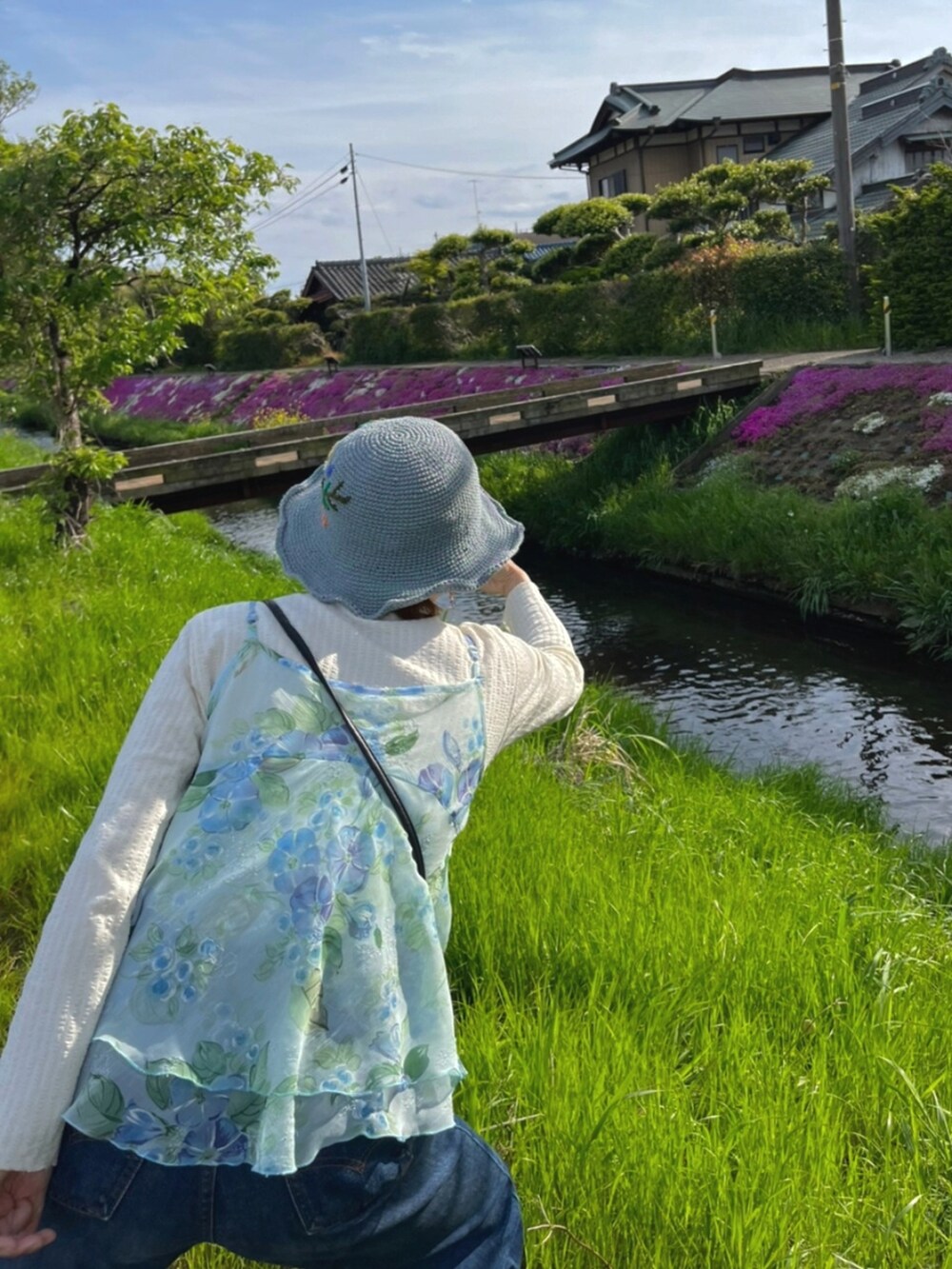 ブルー系のデニムパンツ、ホワイト系のスニーカー、ブルー系のキャミソールを着用したレディースの春コーディネートの2枚目の写真