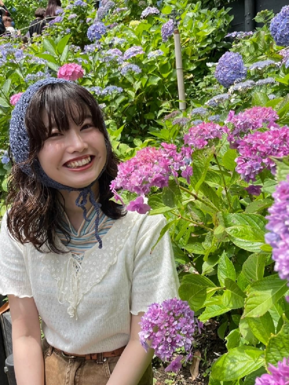 ホワイト系のトップス、ブラウン系のデニムパンツ、シルバー系のハンドバッグを着用したレディースの夏コーディネートの2枚目の写真