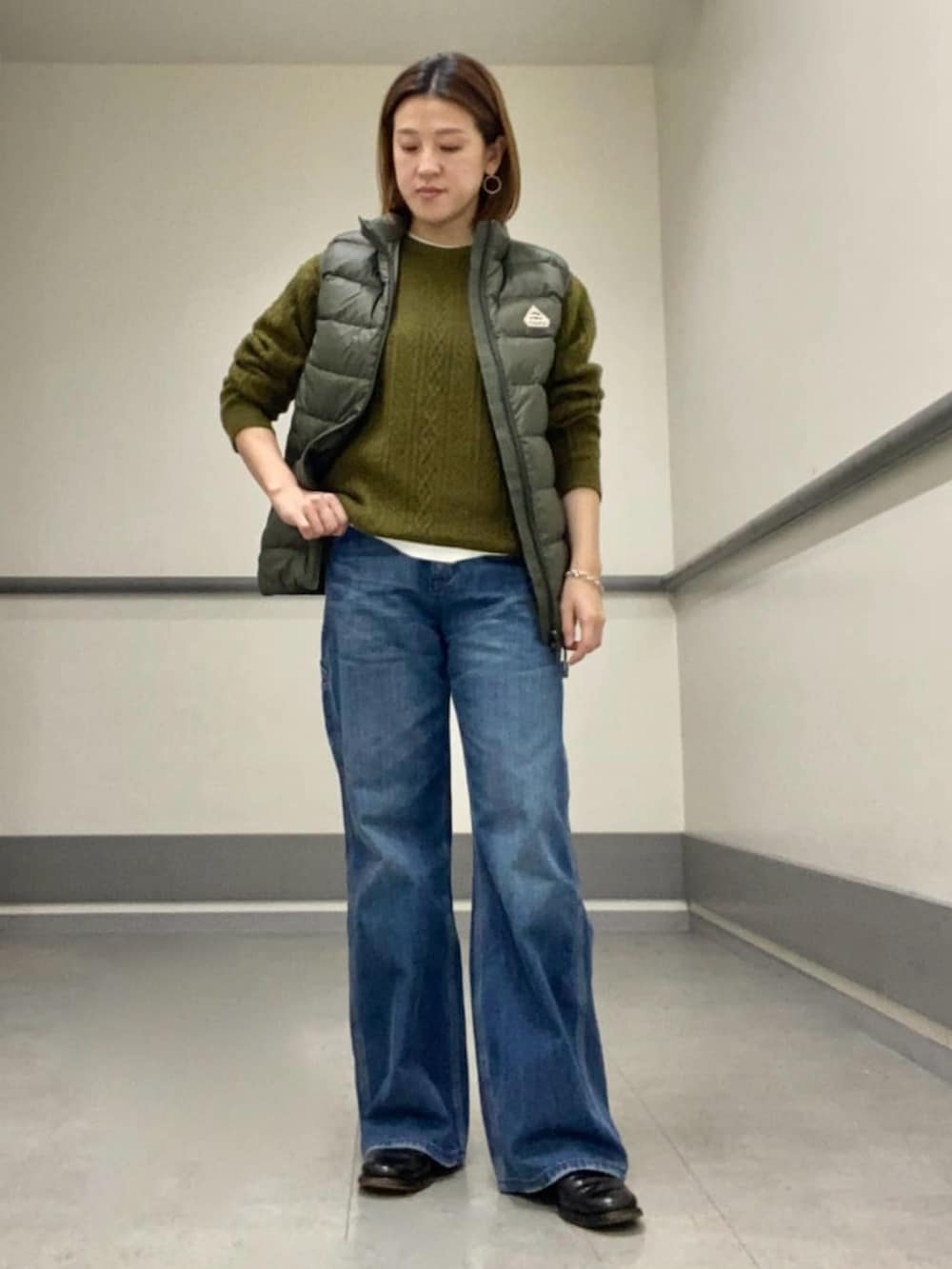 ホワイト系のTシャツ/カットソー、グリーン系のダウンベスト、グリーン系のニット/セーターを着用したレディースの冬コーディネートの2枚目の写真