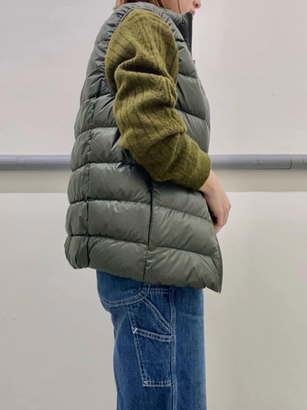 ホワイト系のTシャツ/カットソー、グリーン系のダウンベスト、グリーン系のニット/セーターを着用したレディースの冬コーディネートの3枚目の写真