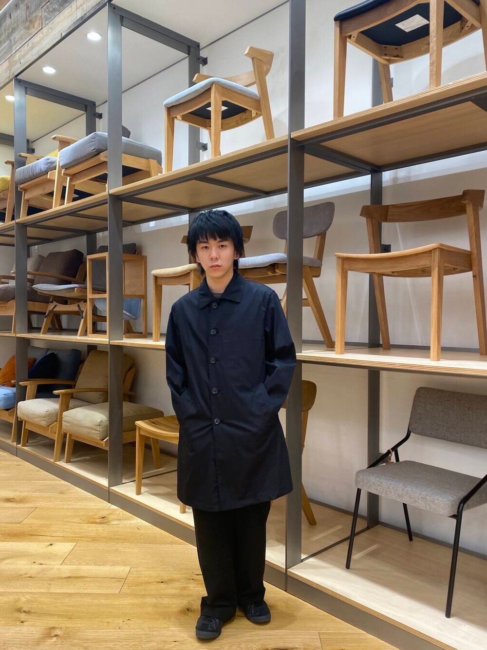 ブラック系のステンカラーコートを着用したメンズの春コーディネートの2枚目の写真