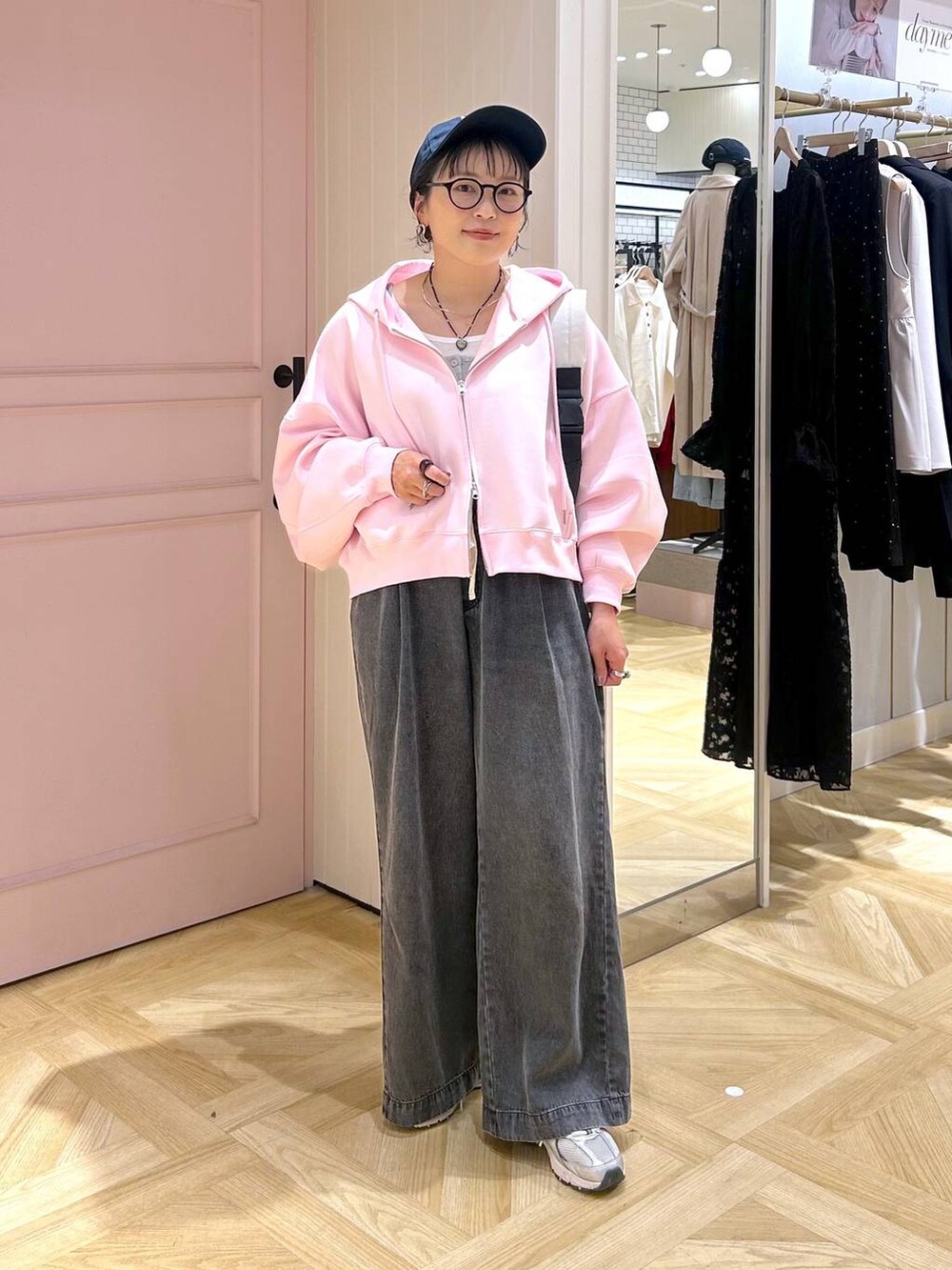 ピンク系のパーカー、ブラック系のデニムパンツ、グレー系のタンクトップを着用したレディースの春コーディネートの6枚目の写真