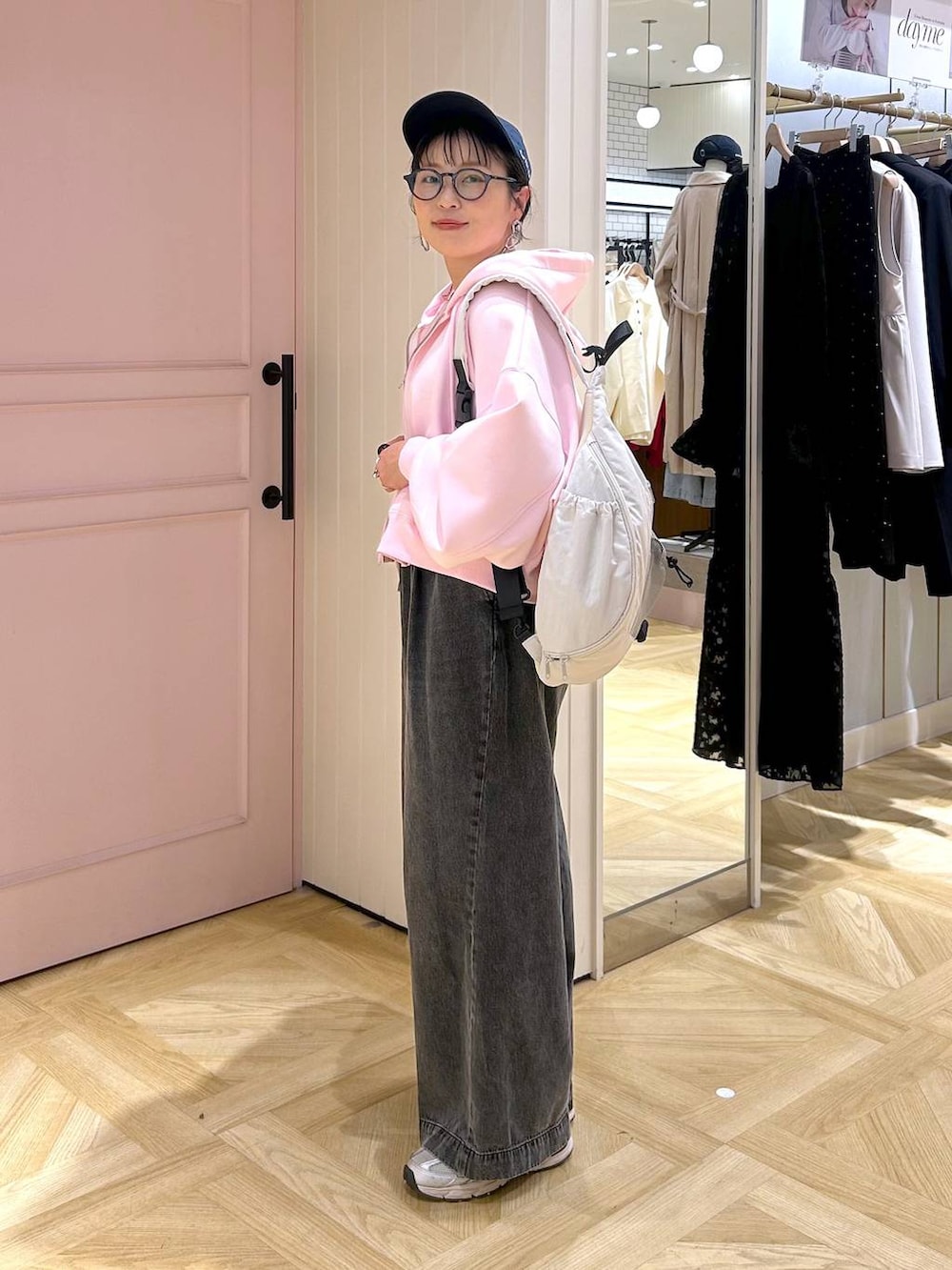 ピンク系のパーカー、ブラック系のデニムパンツ、グレー系のタンクトップを着用したレディースの春コーディネートの3枚目の写真