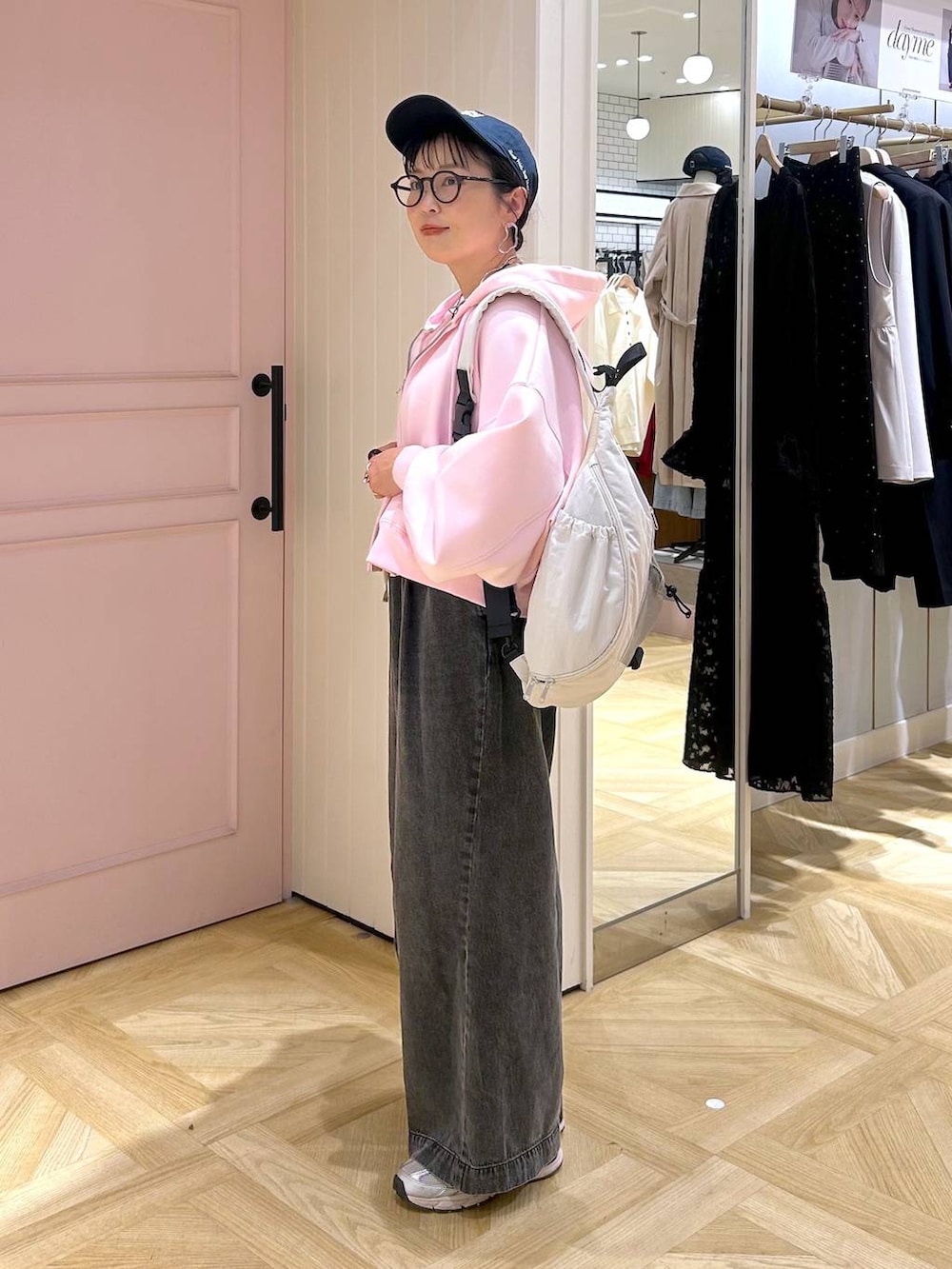 ピンク系のパーカー、ブラック系のデニムパンツ、グレー系のタンクトップを着用したレディースの春コーディネートの2枚目の写真