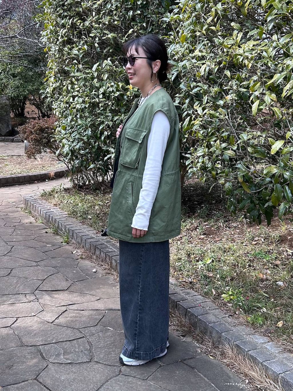 ブラック系のデニムパンツ、ホワイト系のTシャツ/カットソー、ブラック系のベストを着用したレディースの冬コーディネートの3枚目の写真