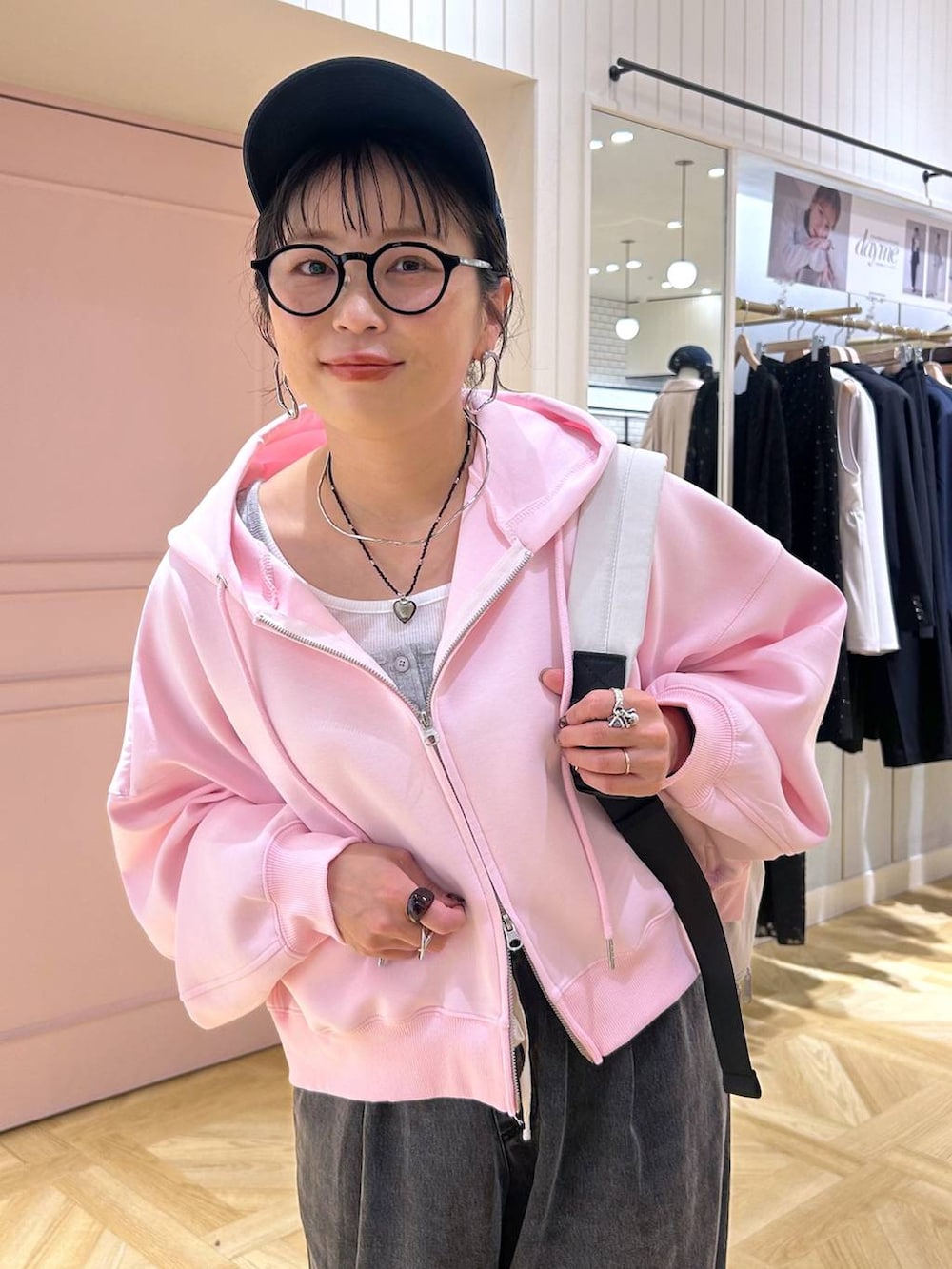 ピンク系のパーカー、ブラック系のデニムパンツ、グレー系のタンクトップを着用したレディースの春コーディネートの9枚目の写真