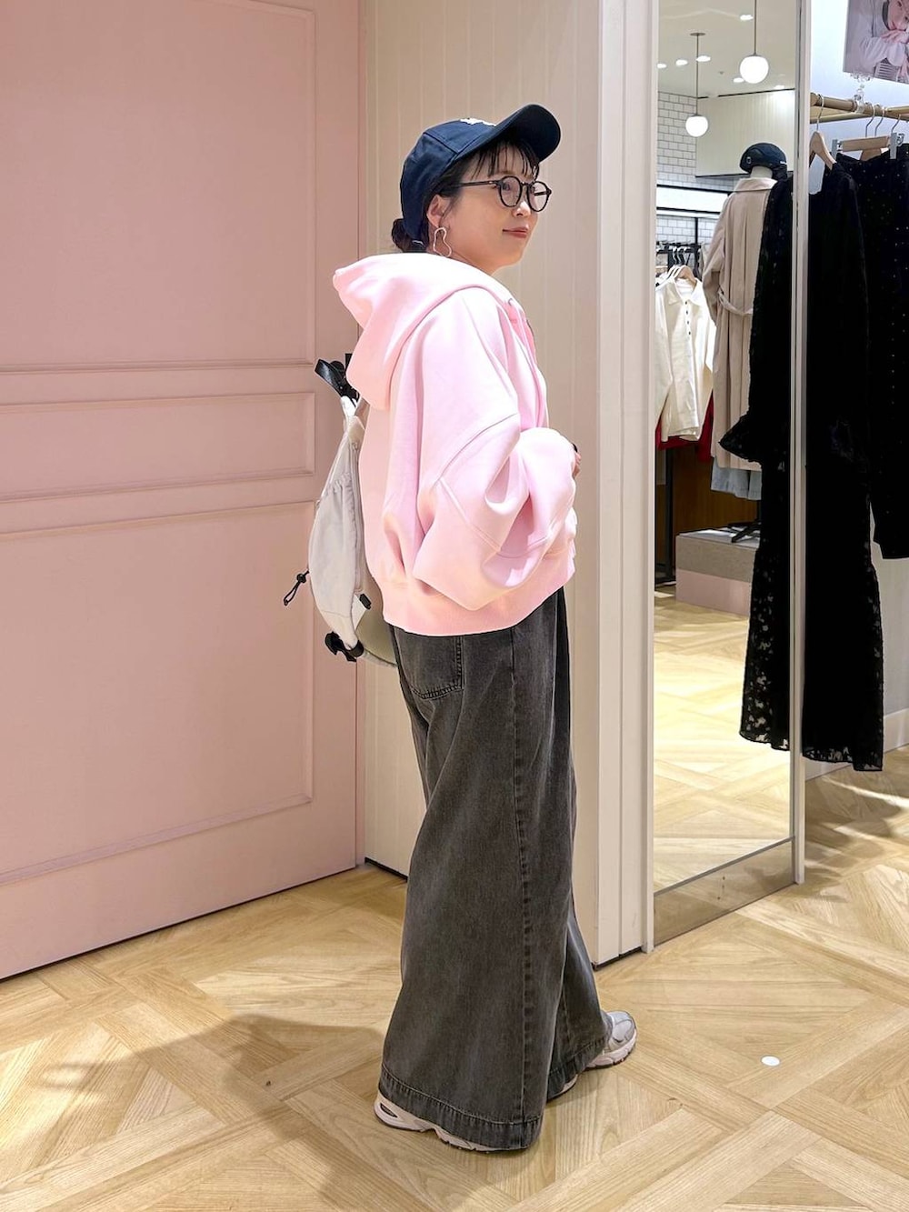 ピンク系のパーカー、ブラック系のデニムパンツ、グレー系のタンクトップを着用したレディースの春コーディネートの5枚目の写真