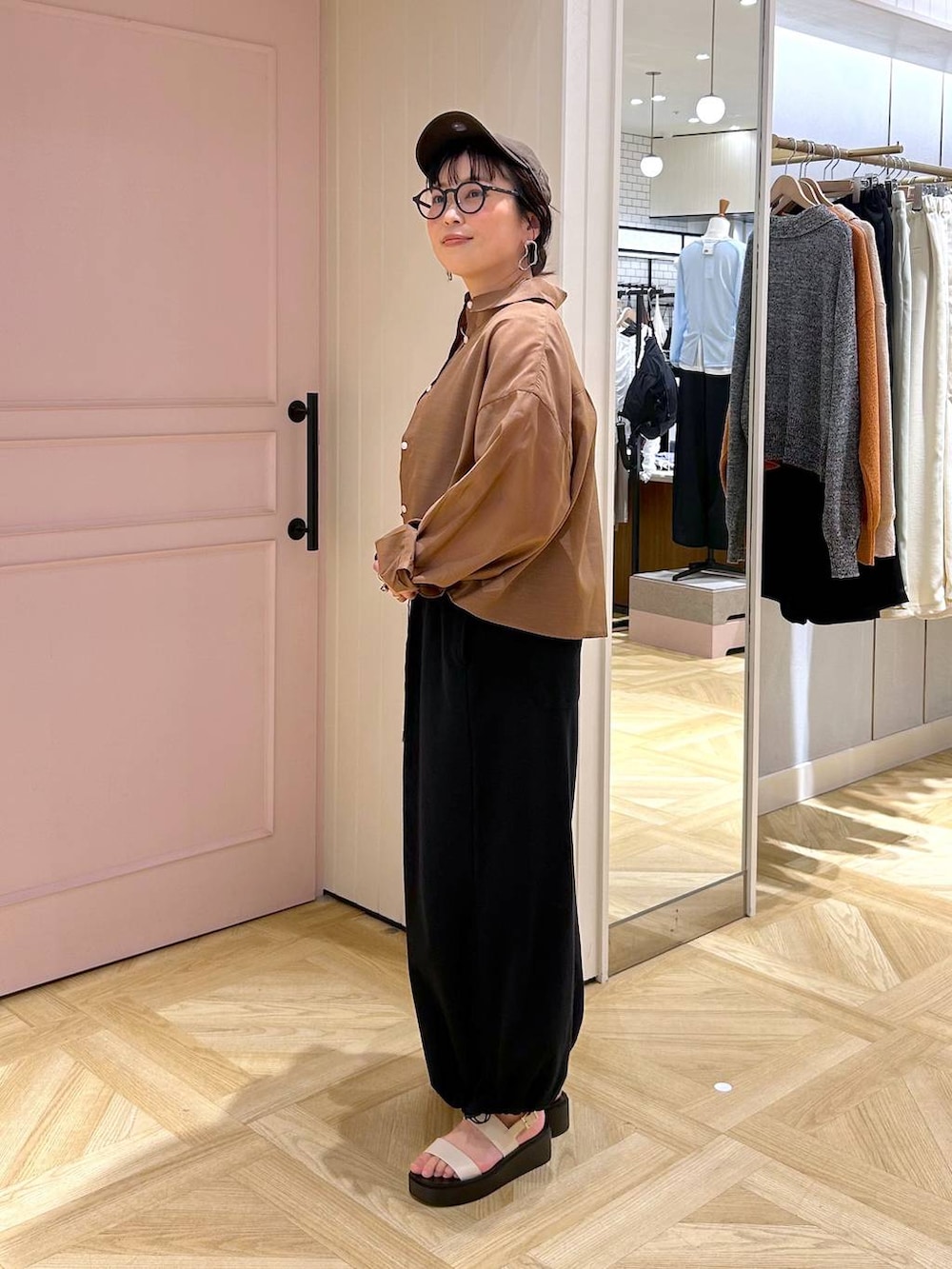 ブラウン系のシャツ/ブラウス、ホワイト系のサンダル、ブラック系のサロペット/オーバーオールを着用したレディースの春コーディネートの3枚目の写真