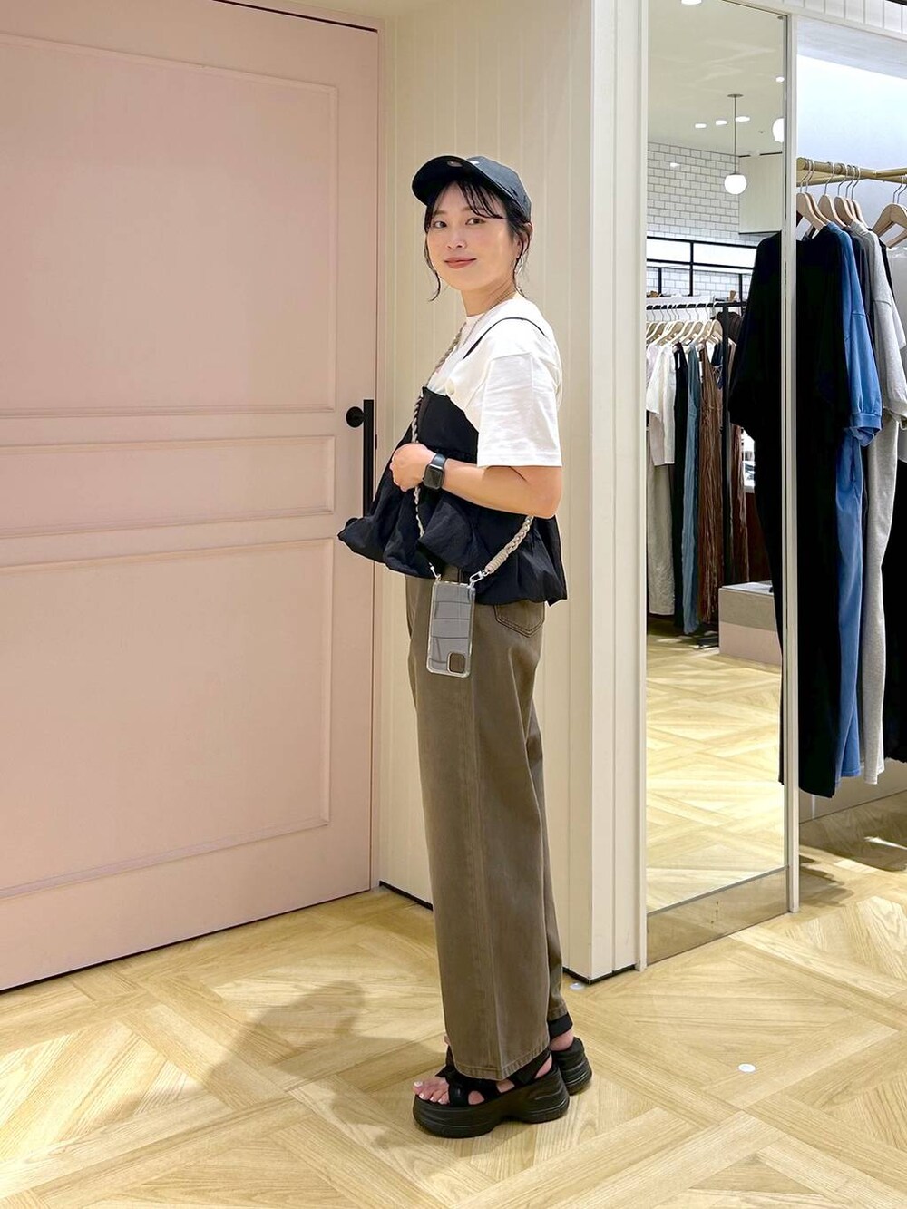 ブラック系のサンダル、ブラック系のキャミソール、ブラウン系のデニムパンツを着用したレディースの春コーディネートの2枚目の写真