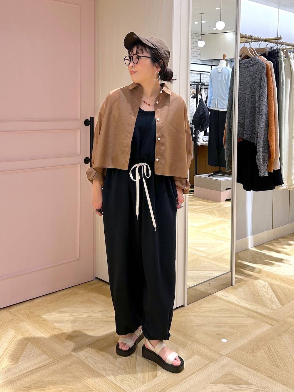 ブラウン系のシャツ/ブラウス、ホワイト系のサンダル、ブラック系のサロペット/オーバーオールを着用したレディースの春コーディネートの2枚目の写真