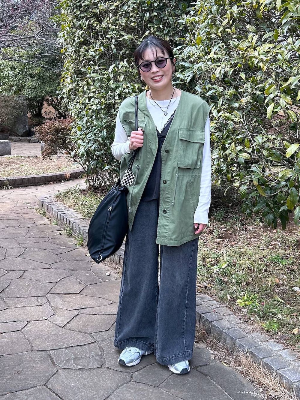 ブラック系のデニムパンツ、ホワイト系のTシャツ/カットソー、ブラック系のベストを着用したレディースの冬コーディネートの2枚目の写真