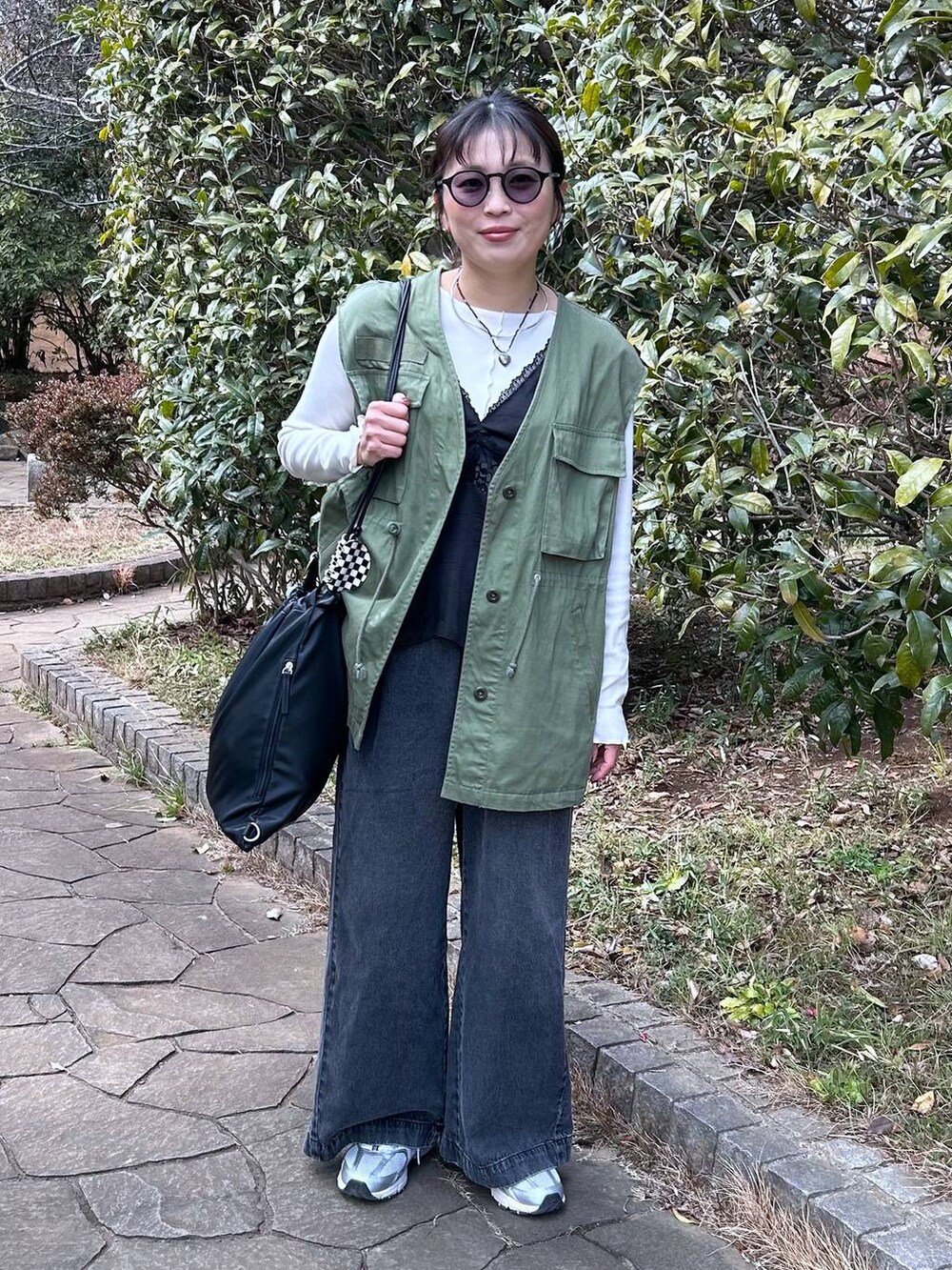 ブラック系のデニムパンツ、ホワイト系のTシャツ/カットソー、ブラック系のベストを着用したレディースの冬コーディネートの6枚目の写真