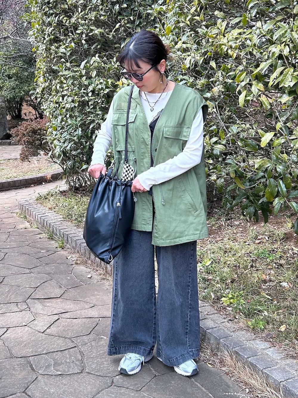 ブラック系のデニムパンツ、ホワイト系のTシャツ/カットソー、ブラック系のベストを着用したレディースの冬コーディネートの5枚目の写真